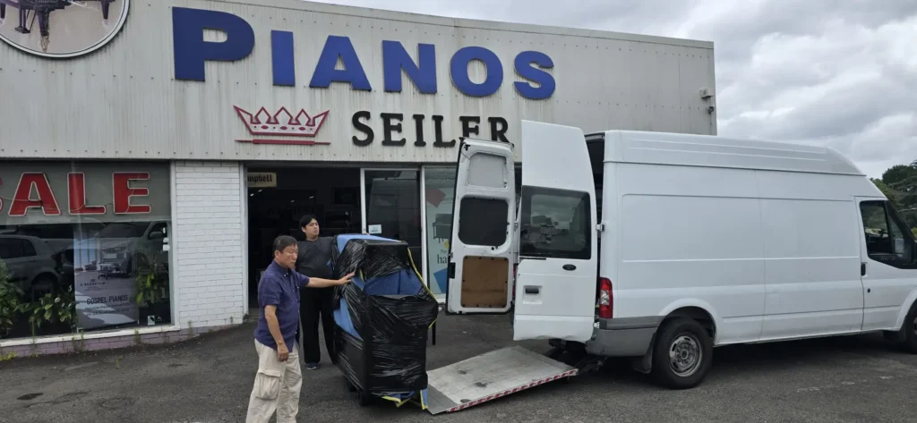 Piano being loaded onto a Piano Pickup van outside the Gospel Pianos showroom on Blaxland Road, Ryde, with Seiler and C. Bechstein signage above the entrance
