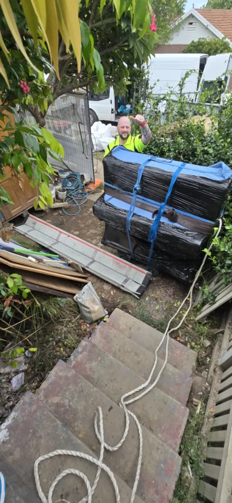 Piano Pickup crew member with an upright wrapped, strapped and trolleyed at the top of a flight of external steps