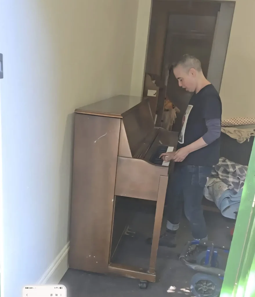 Recipient playing a rehomed upright piano in their bedroom after delivery