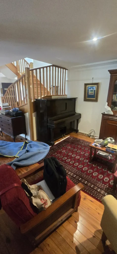 Antique upright piano beside a staircase in a split-level Sydney home before collection